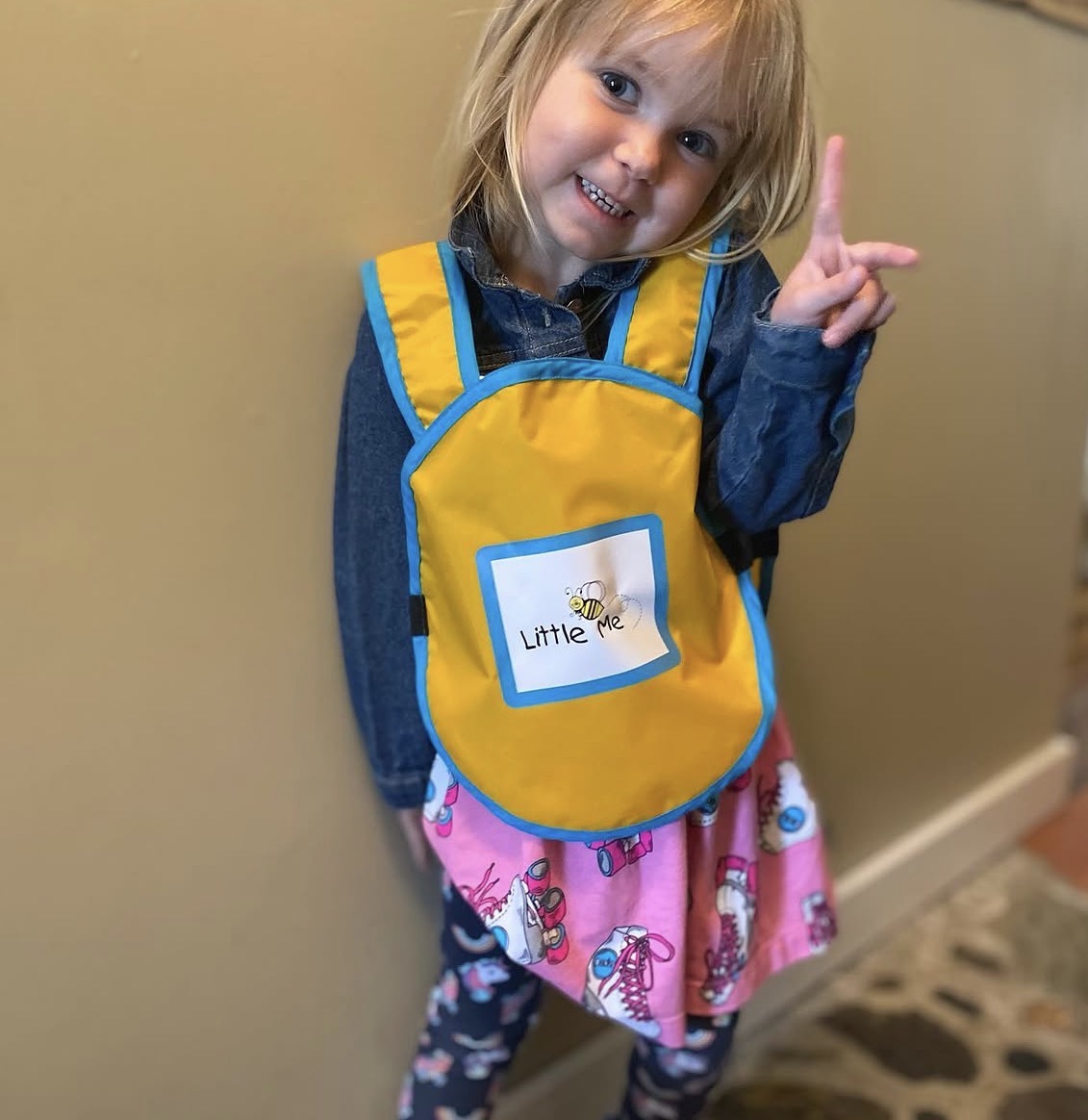 A smiling child wearing a yellow Little Me program vest